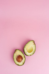 Two halves of brown mature avocado on pink background