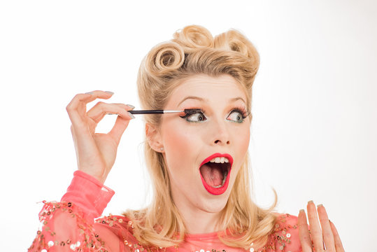 Pinup makeup. Funny woman gets eyebrow correction procedure. Young woman tweezing her eyebrows in beauty saloon. Young woman plucking eyebrows with tweezers close up.