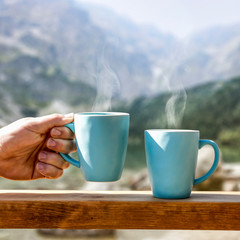 Blue ceramic mugs on wooden handrail and free space for your decoration. 