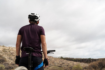 Male trial biker with helmet in mountain cycle resting. Young man looking the sky. Sport and relax concept. Background sky. Image