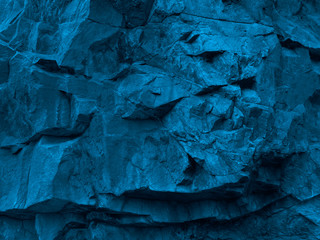 Fototapeta premium Blue grunge background. Toned rock texture. Fragment of a mountain close-up. 3D effect. Petrol color combinations with rough stone texture. Modern bright grunge background.