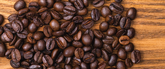 Freshly roasted coffee beans. Background of roasted coffee beans scattered on a wooden table.