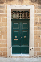 Vintage green wooden door in yellow stone wall
