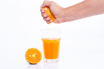 Hand squeezing fresh Orange juice and pieces of orange fruit isolated on a white background