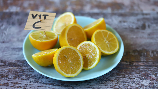 Selective focus. Note with the inscription Vit C in a plate with lemons. Lemons as a source of vitamin C concept.
