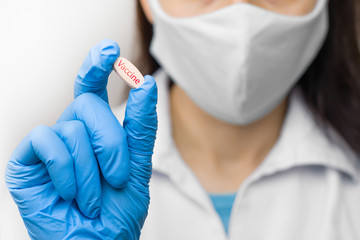 Fototapeta premium A pill in hand in blue gloves. Female is holding a vaccine against coronavirus,2019-nCoV, SARS-nCov, COVID-2019 outbreaking.