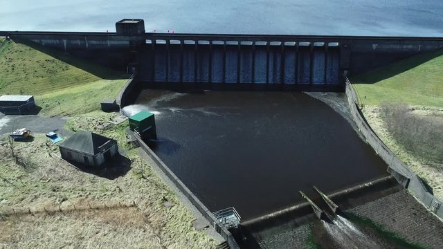 Low level aerial footage over a reservoir dam. 