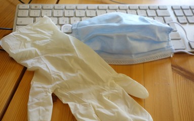 Virus season, pandemic. Smart working in order to prevent the spread of respiratory diseases like coronavirus COVID-19. Latex glove and surgical mask on a computer keyboard