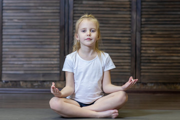 girl child doing exercises doing yoga on a Mat in the Studio or at home . the child is engaged in...