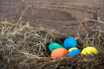 Easter eggs in a basket on a hay with a blurred background