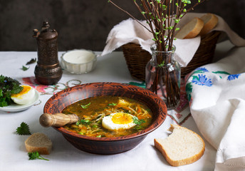 Spring green soup with herbs, vegetables and green peas, served with egg and sour cream. Rustic style.
