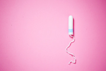 Medical female tampon on a pink background with copy space. Hygienic white tampon for women. Cotton swab. Menstruation, means of protection. - obrazy, fototapety, plakaty