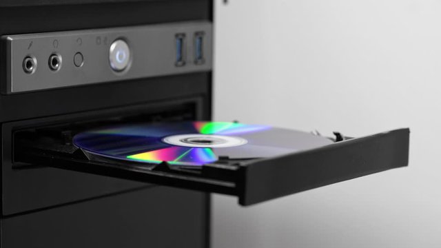 A male hacker programmer opens a drive with a CD-DVD drive. Obsolete storage medium.
