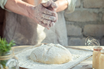 Baker man holds hands over the bread from whole wheat flour rustic style