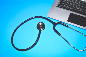 Laptop with doctor's stethoscope on a blue background