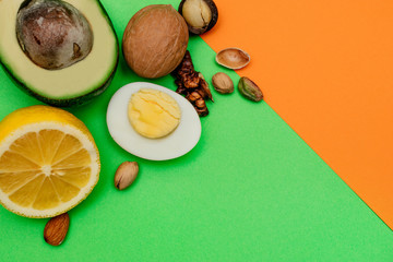 Flat lay ketogenic diet. Аvocado,egg,lemon and nuts on the green and orange backgrounds. Concept of healthy food,top view.Copy space for mock up