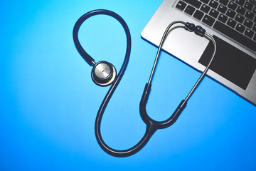 Laptop with doctor's stethoscope on a blue background