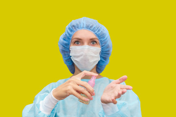 Female doctor treats hands with antiseptic gel. Portrait of doctor in scrubs.