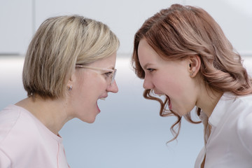 Mom and her teen daughter shout at each other forehead. Relationship problems, transitional period