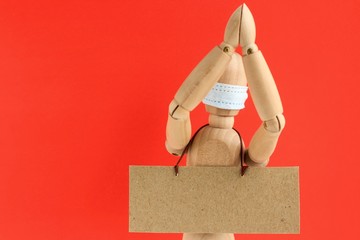 Cardboard sign with space for text hanging on a wooden doll or mannequin in a medical mask. Concept...