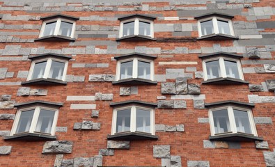 nine windows on a red brick wall and gray stones