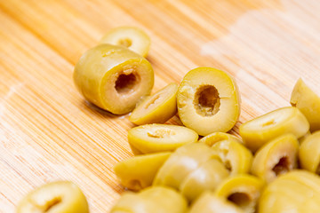 Green olives cut in pieces slices lying on wooden board