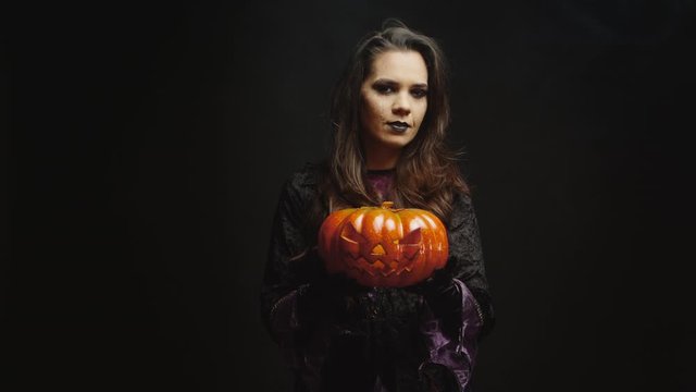 Young woman dressed up like a witch holding a pumpking