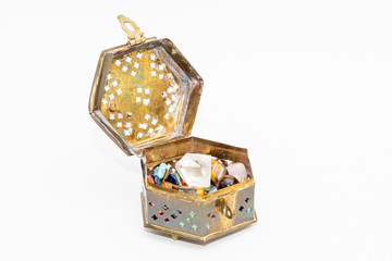 Raw diamond dob between colorful gemstones in old jewelry box