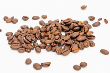 Roasted coffee beans spread out on white underground