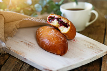 Sweet bun and a cup of tea and a knife on a wooden table. Pies. View from above
