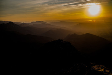 Dark silhouettes of the Carpathian rocky mountains and sunset sky with a large yellow sun