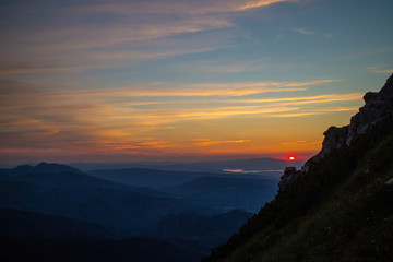 Blue silhouettes of Carpathian rocky mountains and sunset orange-blue sky with clouds