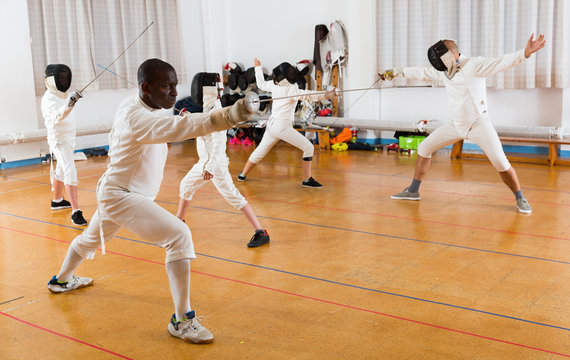 African American wearing fencing uniform practicing with foil