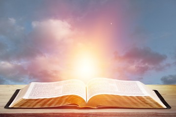 Open book on old wooden table on sky background