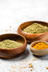 Ayurvedic hair care products. Henna, turmeric and neem powder in bowls on a grey background. Natural care and hair coloring.	