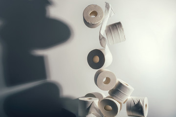Falling rolls of toilet paper on white background with dark shadow. Concept of crisis, quarantine,...
