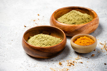Ayurvedic hair care products. Henna, turmeric and neem powder in bowls on a grey background. Natural care and hair coloring.	