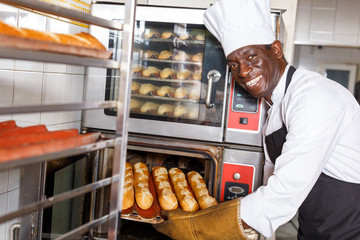 Baker taking out bread from oven