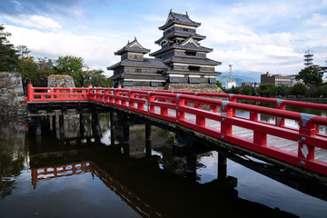 Matsumoto Castle with reflection on the pond and red bridge, Matsumoto, Nagano, Japan	
