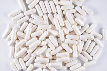 Closeup of a pile of white medicine capsules (top view)