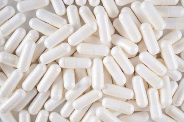 Fototapeta na wymiar Closeup of a pile of white medicine capsules (top view)