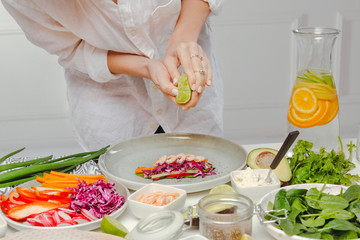 Woman's hands adding lime juice to spring roll. Photo recipie of asian dish. Healthy and tasty food.