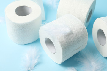 Toilet paper and feathers on blue background, close up