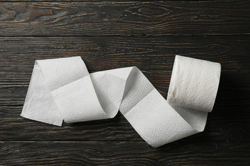 Roll of toilet paper on wooden background, top view