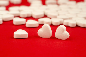white plastic bottle and scattered white pills on red table.