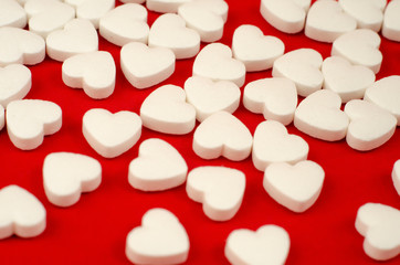 white plastic bottle and scattered white pills on red table.