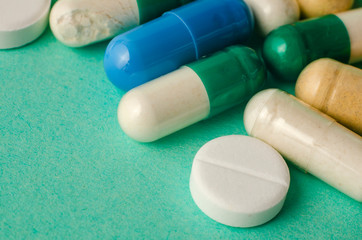scattered mixed colorful medication pills on red table.