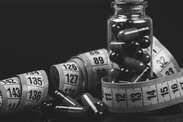 Glass bottle with diet pills and measuring tape