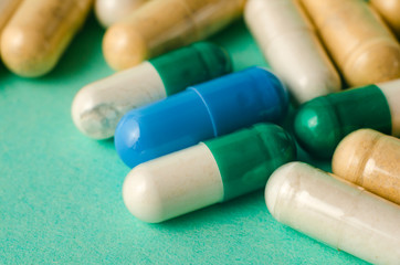 scattered mixed colorful medication pills on red table.