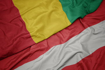 waving colorful flag of austria and national flag of guinea.